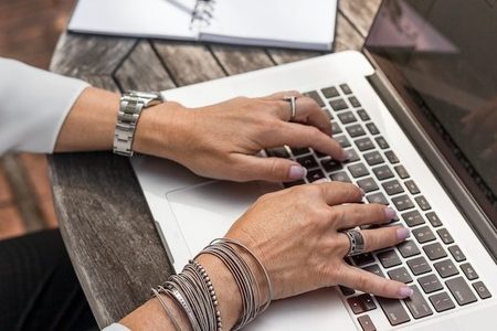 person using a guide to grants for nonprofits to write a grant proposal on a laptop computer